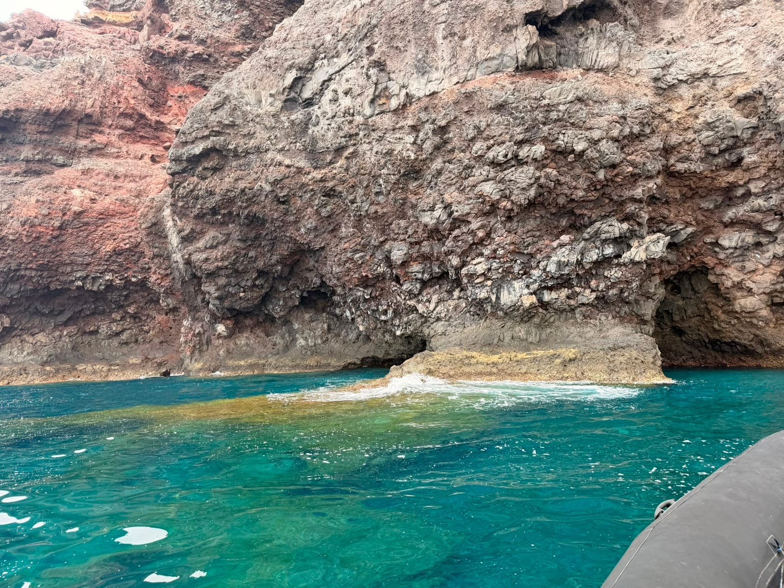 Zeegrot en rotsboog boven turquoise water, vlak naast de boot