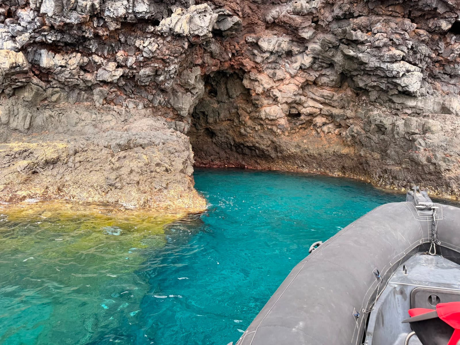 Zeegrot en rotsboog boven turquoise water, vlak naast de boot