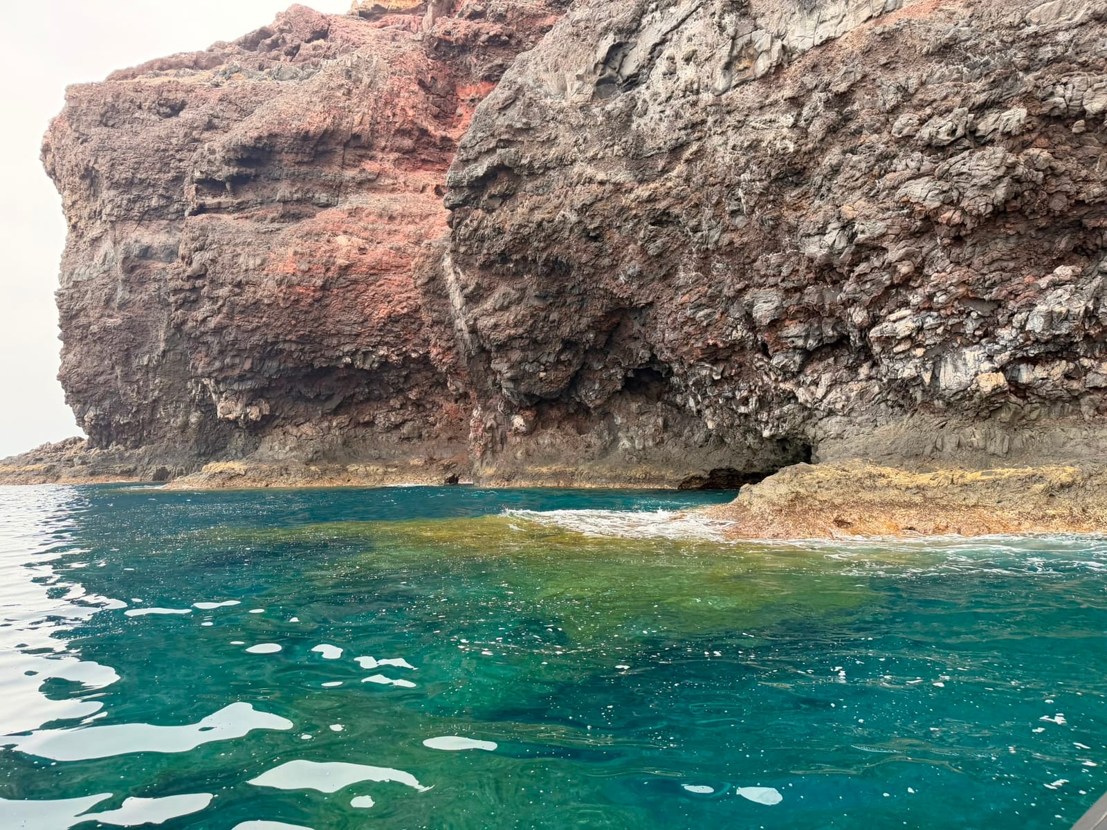 Zeegrot en rotsboog boven turquoise water, vlak naast de boot